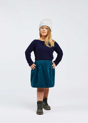 woman with dwarfism wearing blue corduroy skirt and dark blue pullover