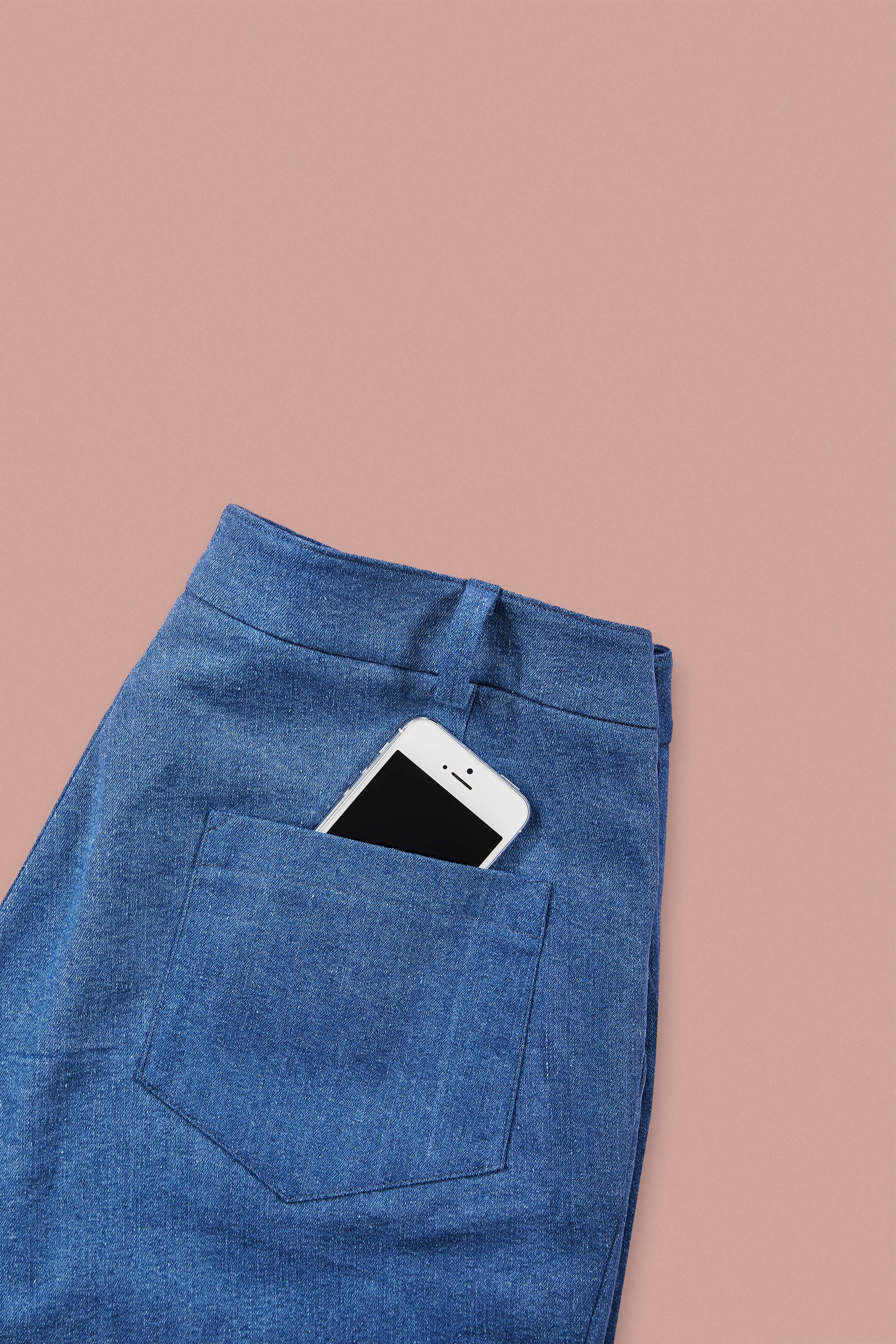 detailed view of pocket in blue denim shorts on rose background