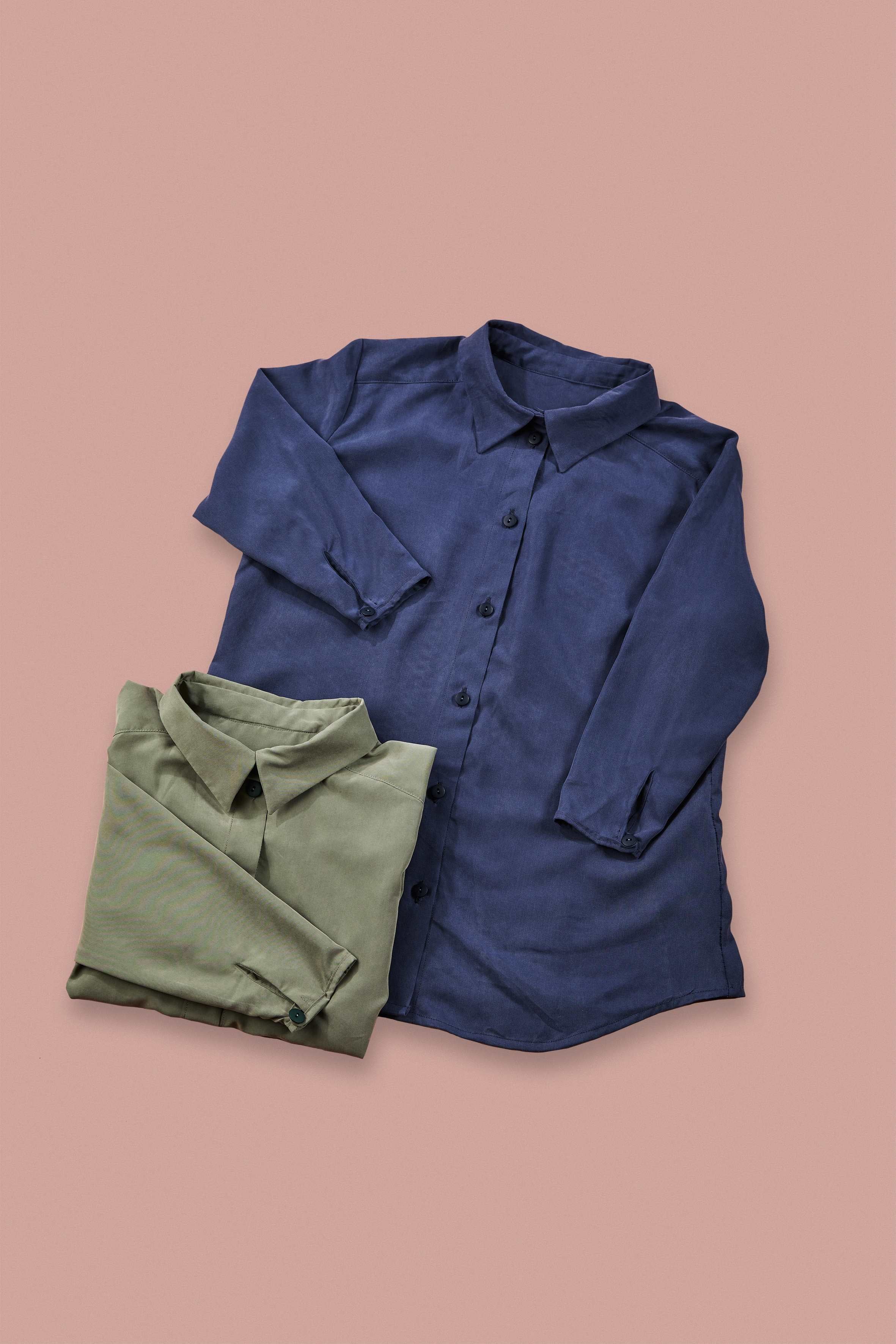 blue blouse and folded up green blouse on rose background