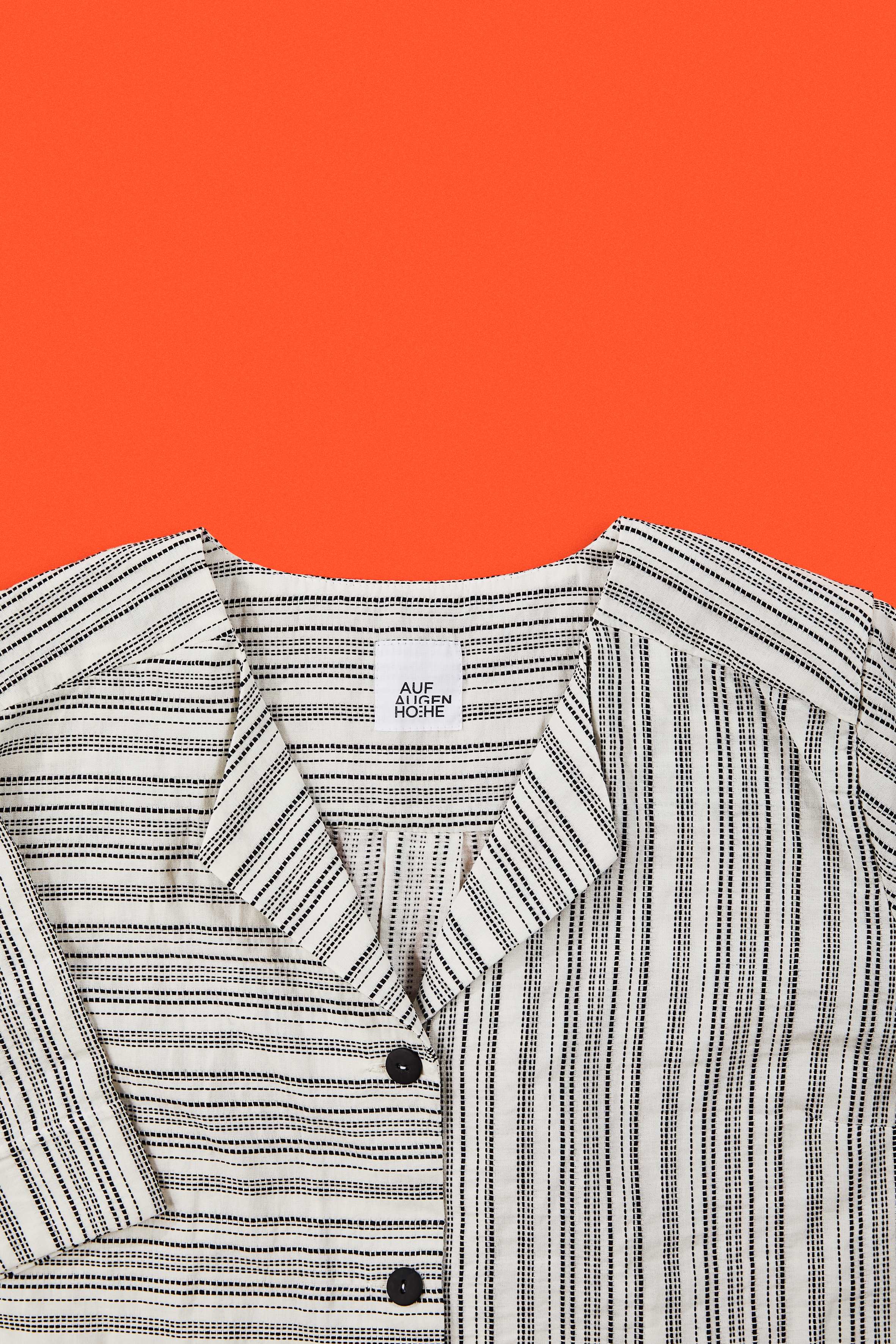detailed view of black and white striped blouse on orange red background
