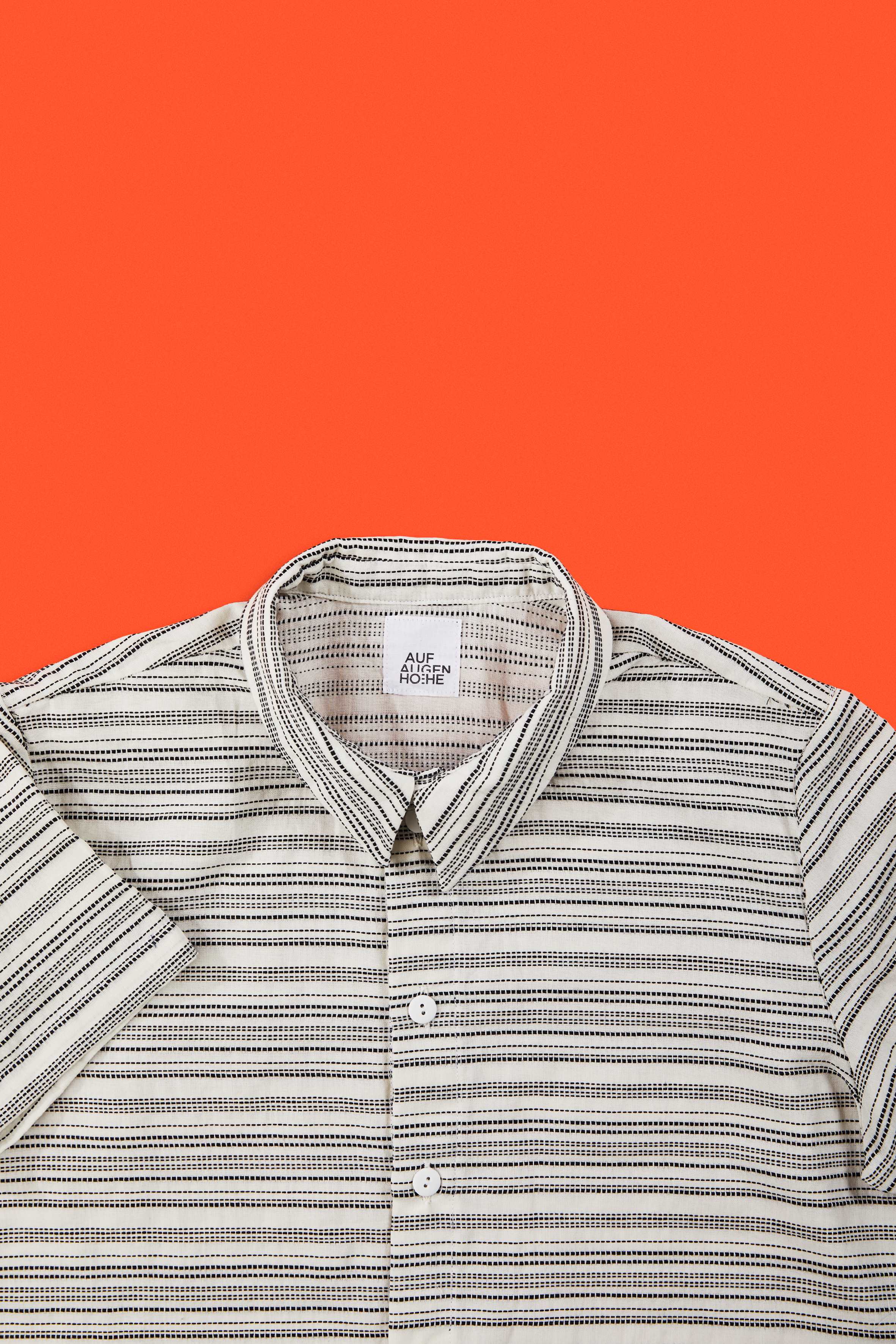 detailed view of black and white striped shirt collar against orange background