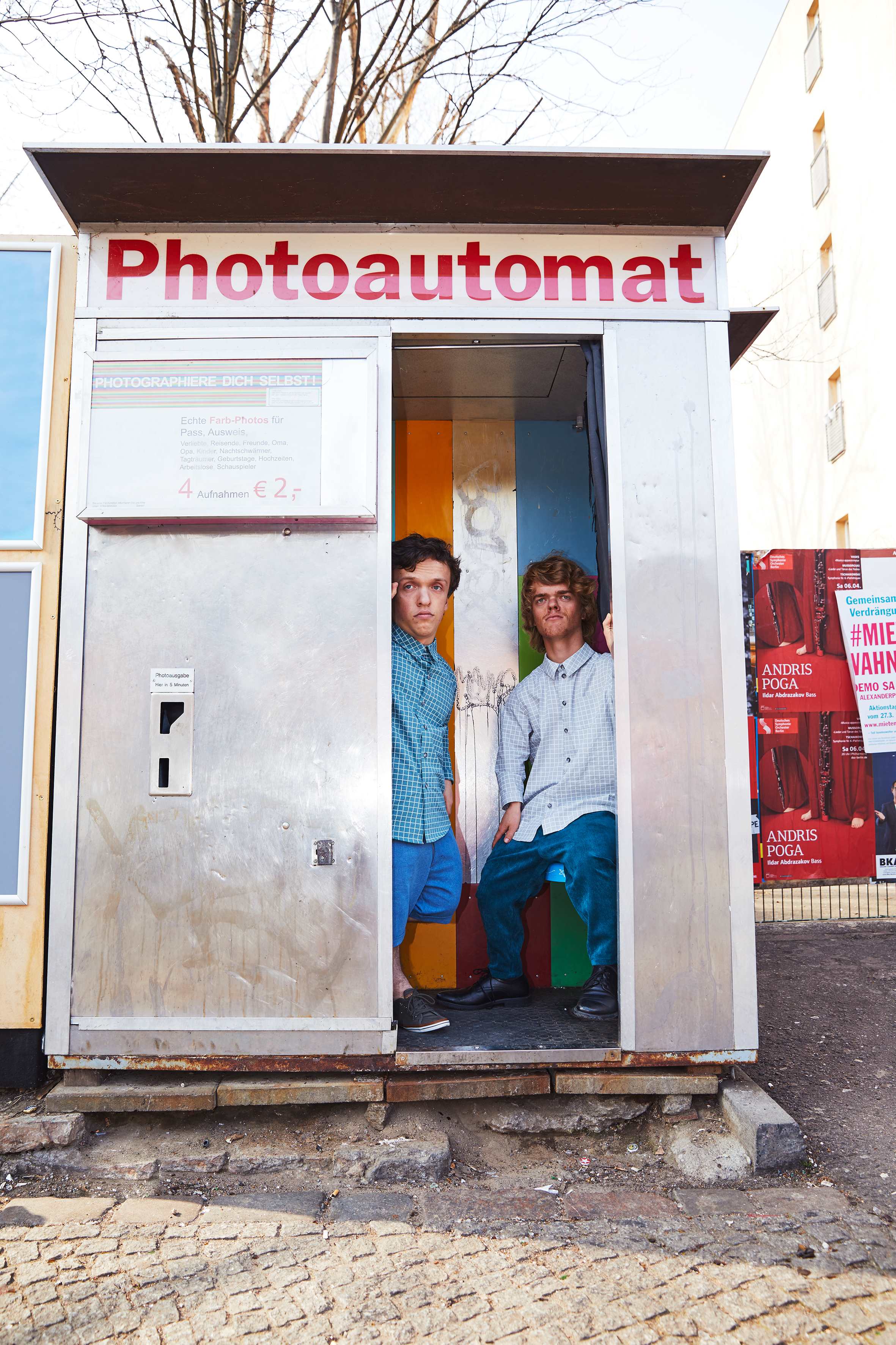 two men with dwarfism looking out of a photobooth in berlin