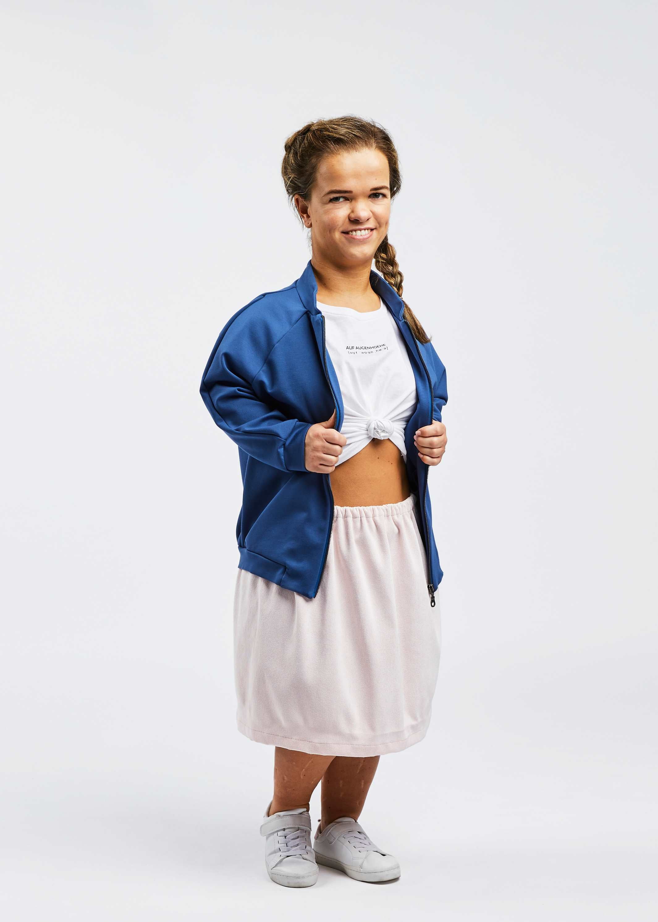 woman with dwarfism wearing blue college jacket and romantic outfit