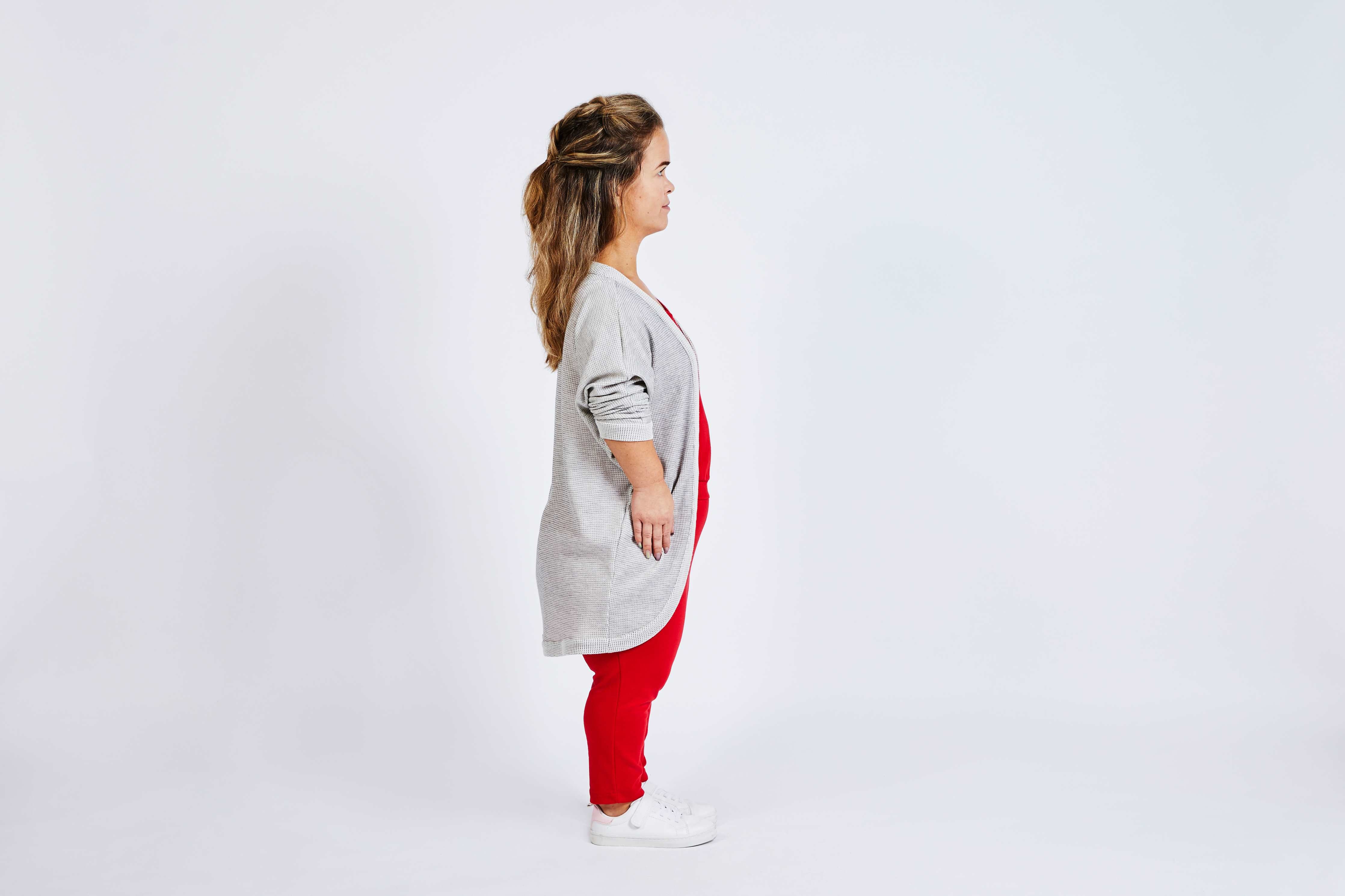 sideview of woman with dwarfism with red jumpsuit and grey cardigan
