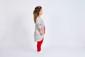 sideview of woman with dwarfism with red jumpsuit and grey cardigan