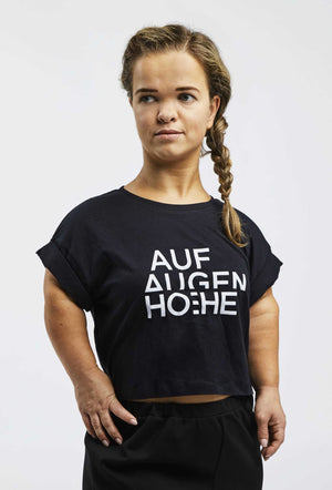 woman with dwarfism wearing black cropped t-shirt with big brand logo