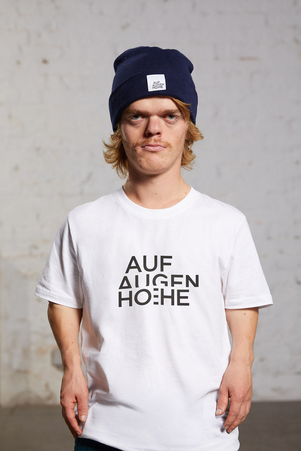man with dwarfism wearing a white t-shirt with black brand logo