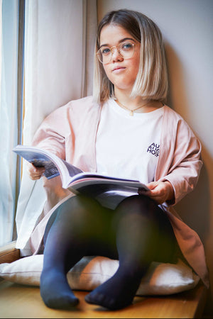 woman with dwarfism lounging with a magazine at a window