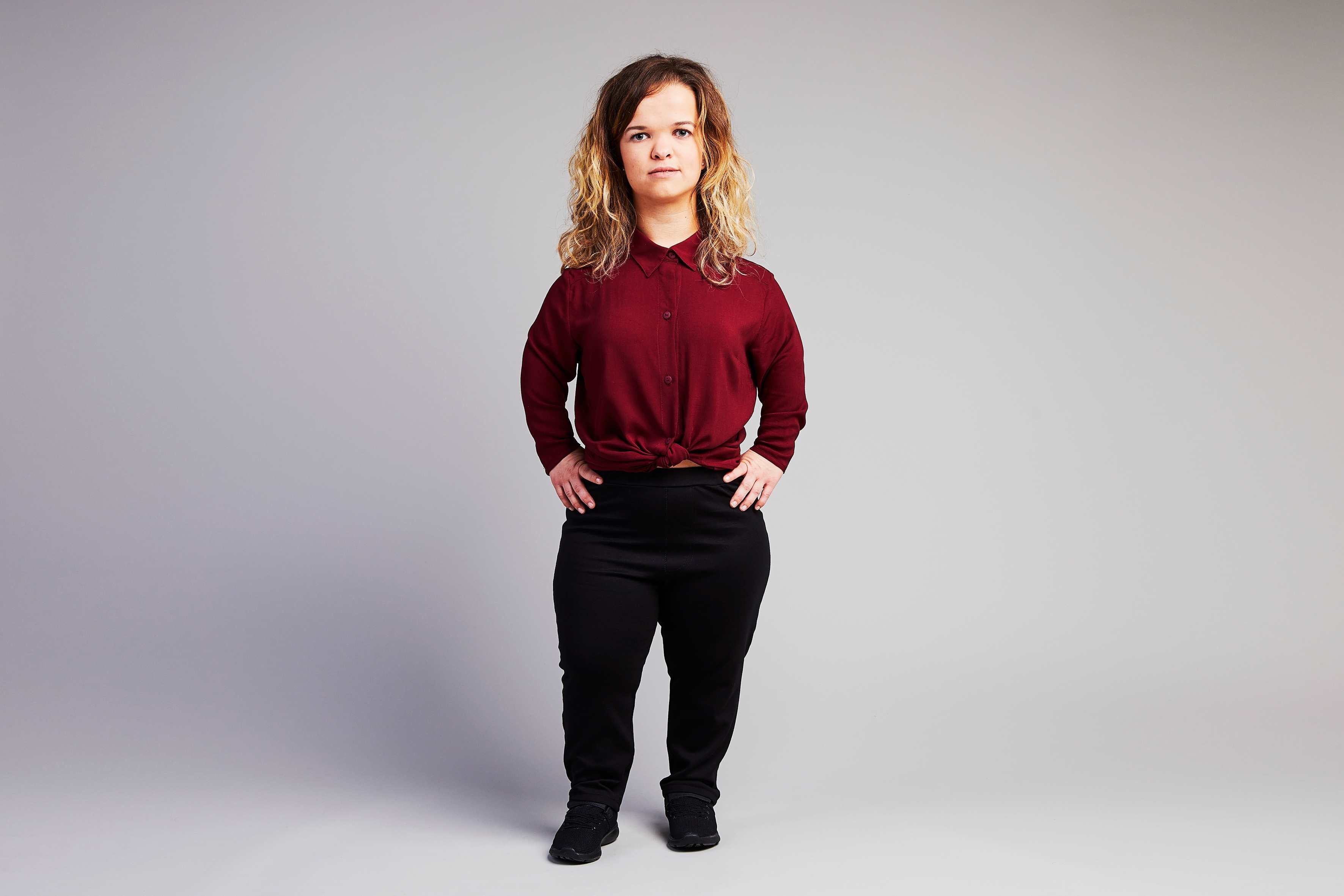 woman with dwarfism wearing red blouse and black pants