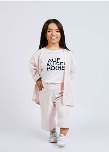 woman with dwarfism wearing pastel rose jacket with matching pants and white shirt