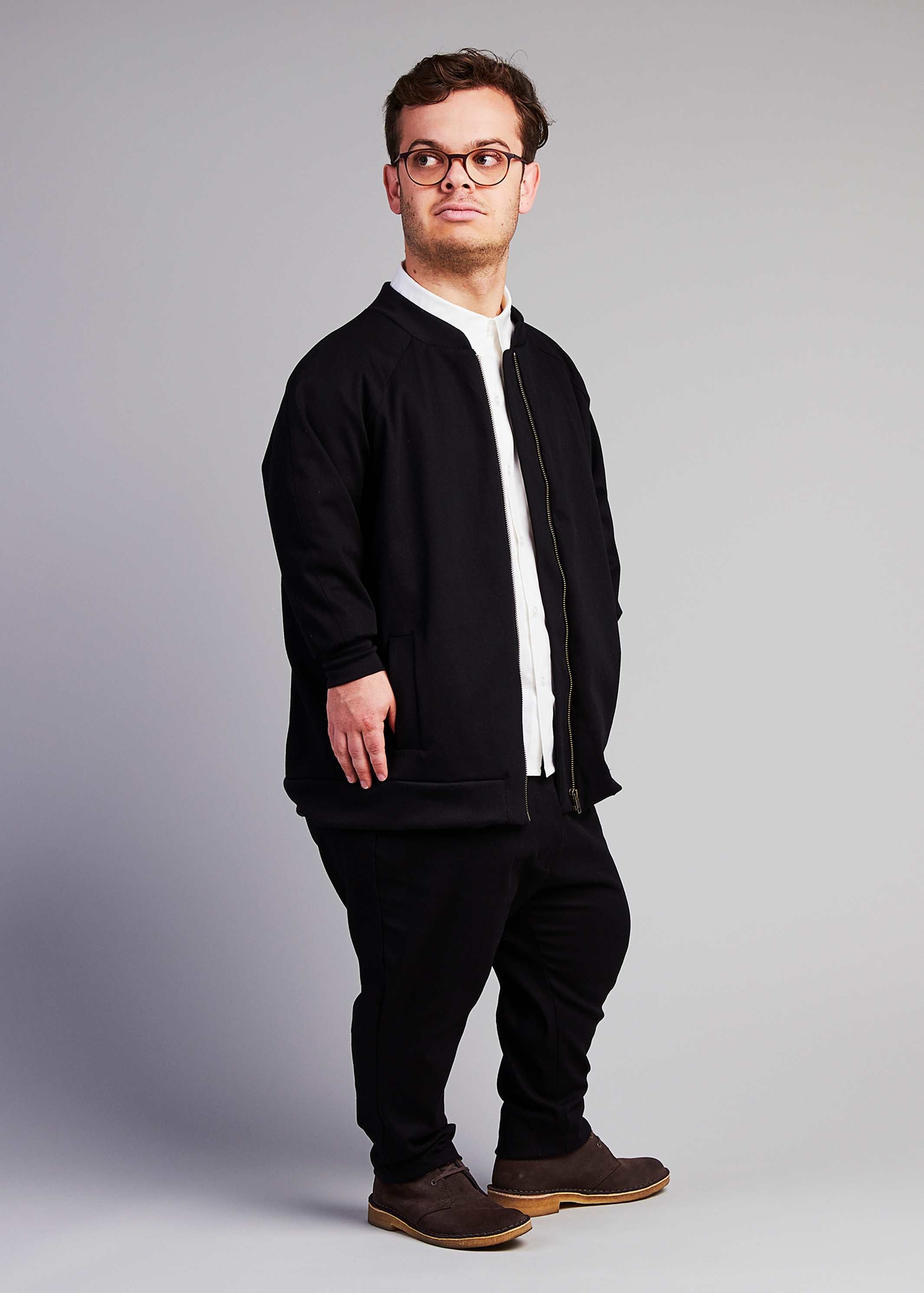  man with dwarfism wearing black college jacket and matching outfit