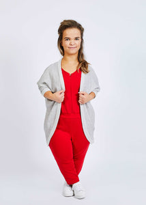 woman with dwarfism wearing bright red jumpsuit and grey cardigan