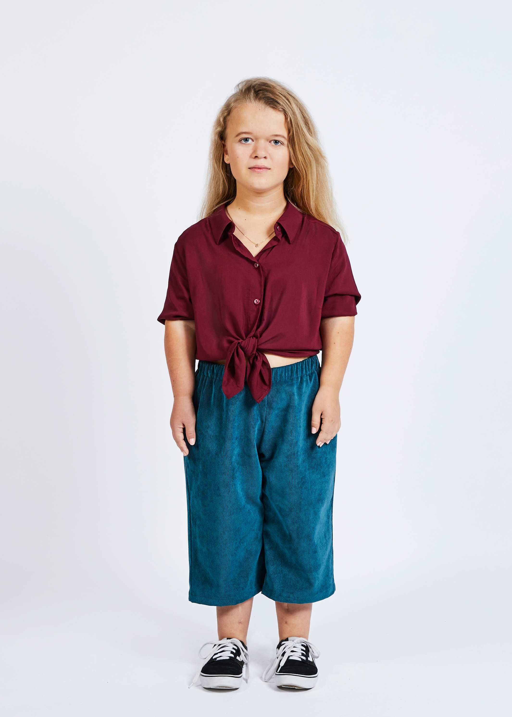 woman with dwarfism wearing corduroy blue pants with burgundy red blouse