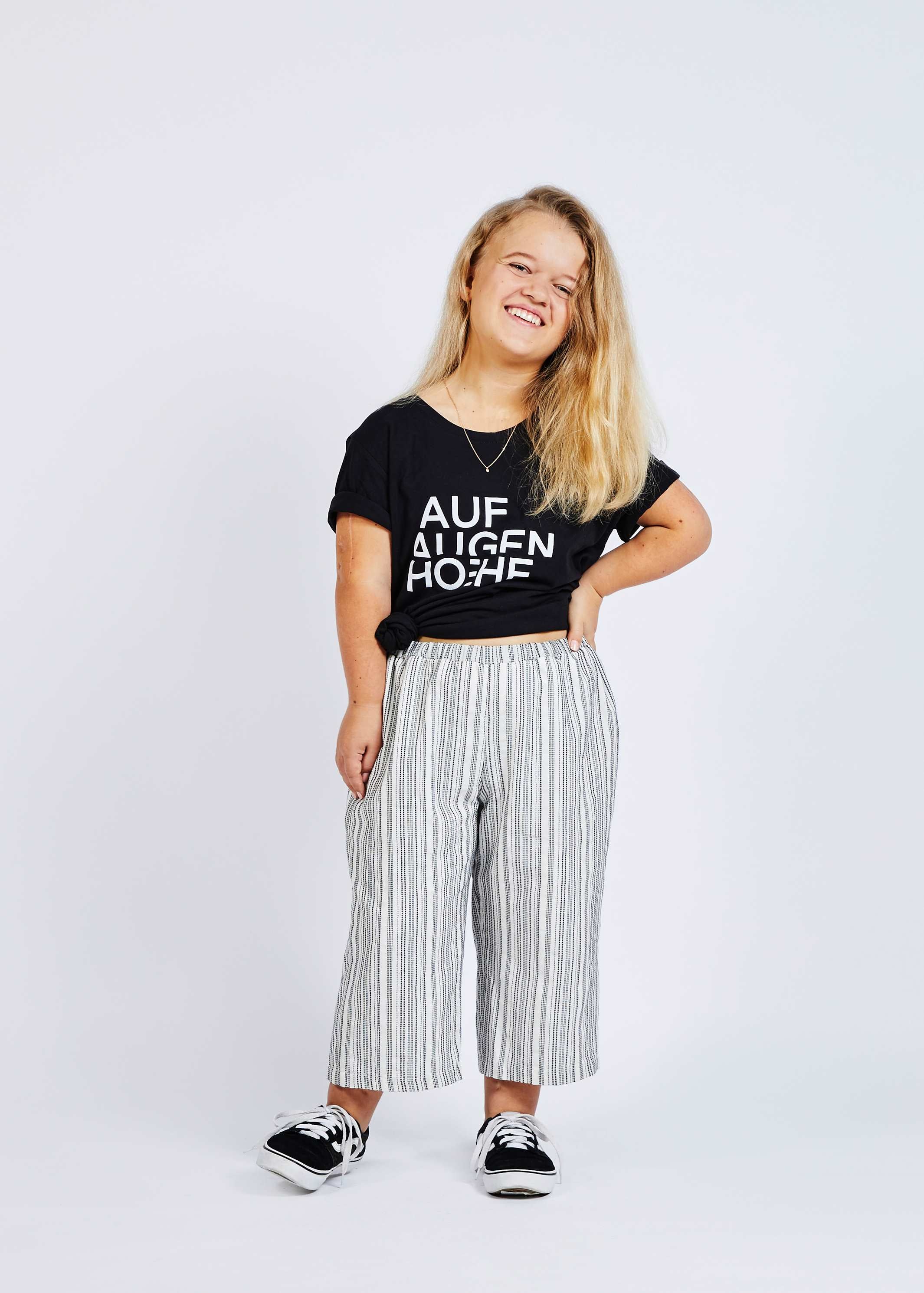 woman with dwarfism wearing black and white striped pants and black t-shirt