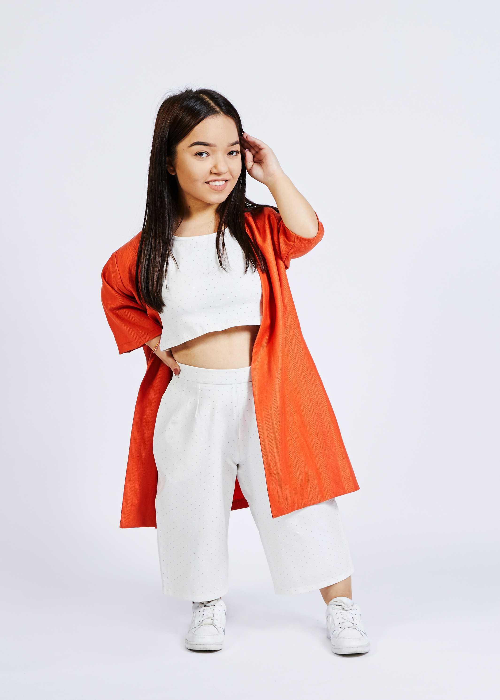 woman with dwarfism wearing bright red kimono, white pants and white crop top