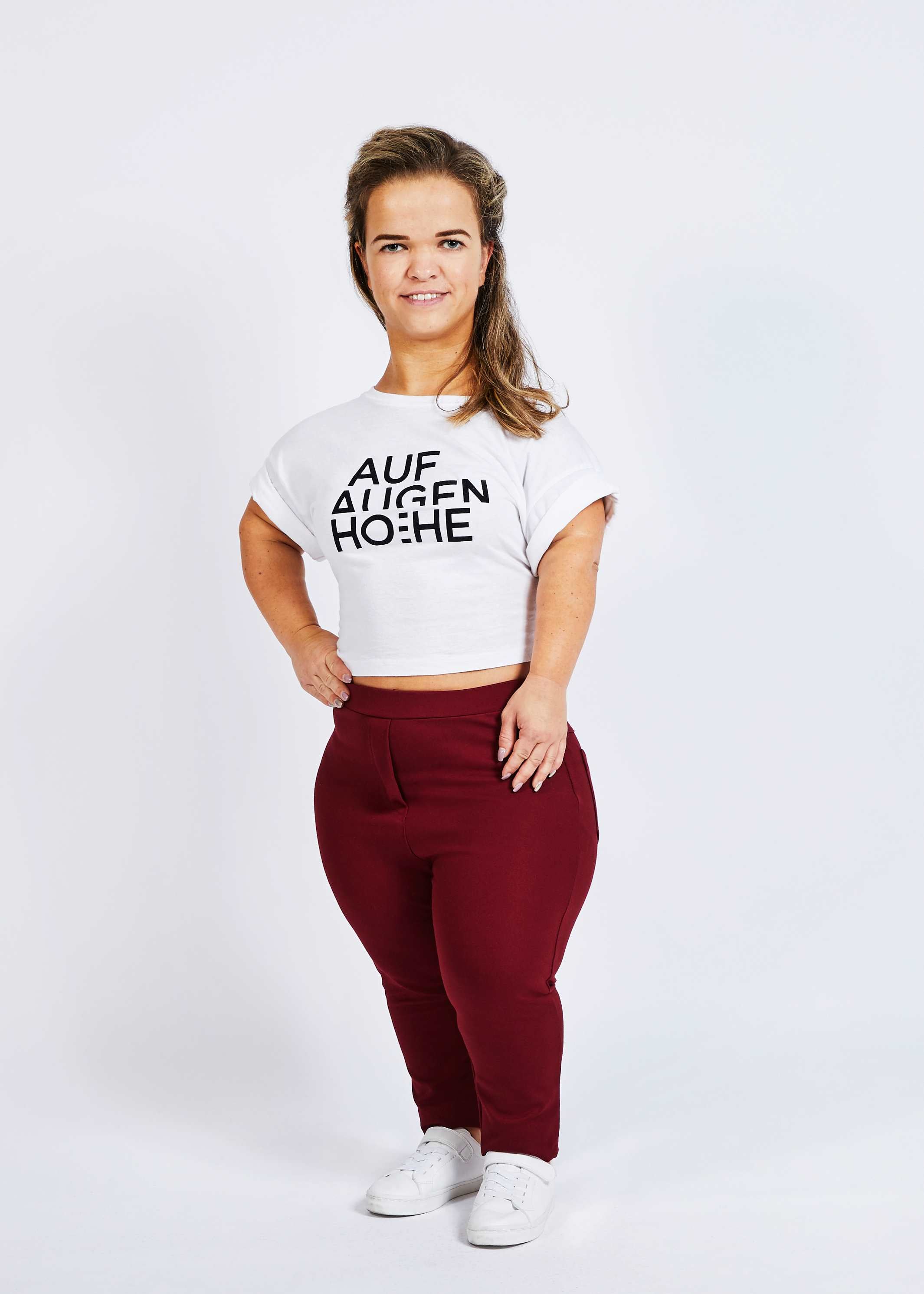 woman with dwarfism wearing wine red pants and white shirt