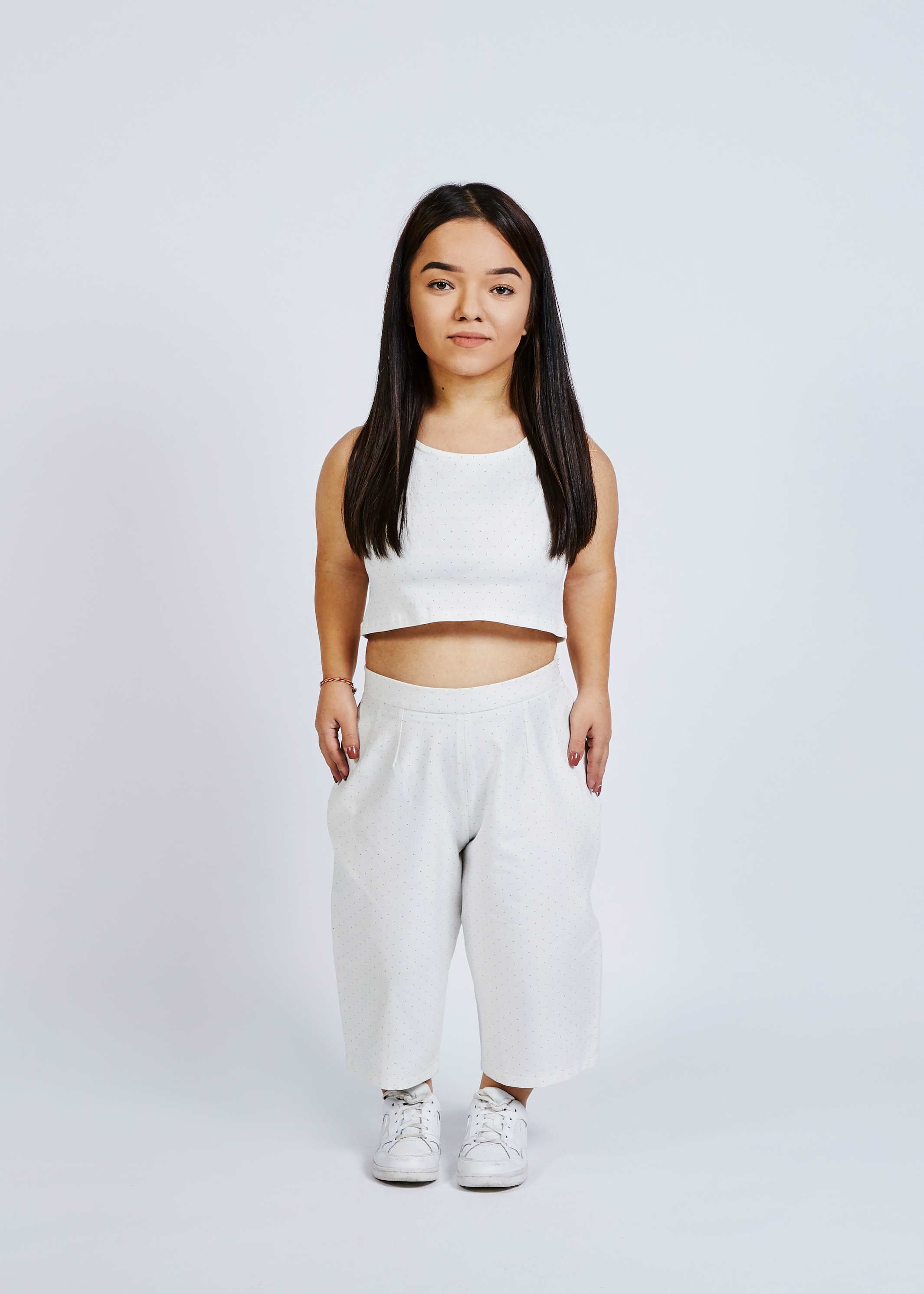 woman with dwarfism wearing white culottes with small dots and matching crop top