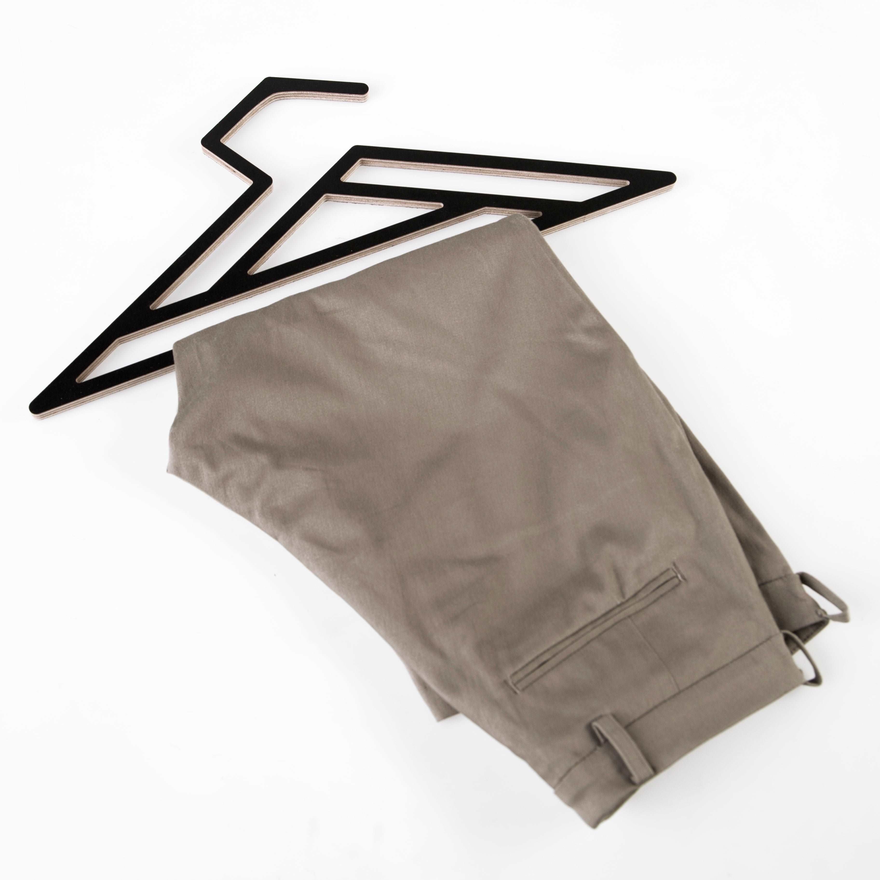 dress hanger in geometric design in black with a pair of pants hanging from it